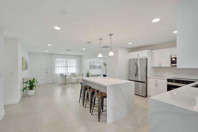 kitchen featuring pendant lighting, white cabinets, light stone counters, and stainless steel appliances