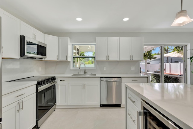 kitchen with appliances with stainless steel finishes, sink, beverage cooler, and a wealth of natural light