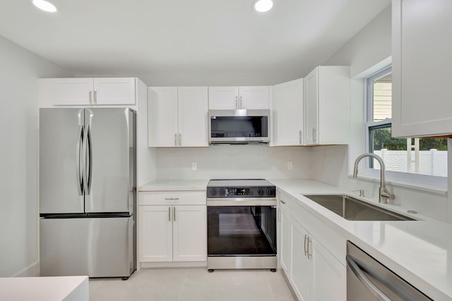 kitchen featuring sink, appliances with stainless steel finishes, white cabinets, and light tile patterned floors