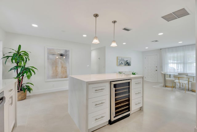 kitchen with wine cooler, white cabinets, hanging light fixtures, stainless steel dishwasher, and a center island