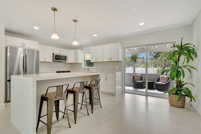 kitchen with a center island, white cabinets, hanging light fixtures, and stainless steel appliances