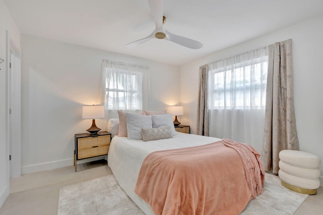 tiled bedroom featuring multiple windows and ceiling fan