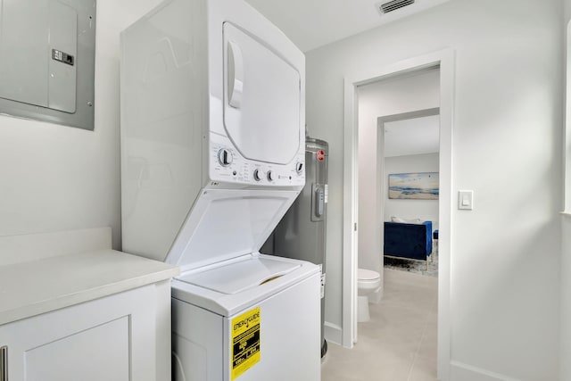 washroom featuring light tile patterned flooring, electric panel, and stacked washer and clothes dryer