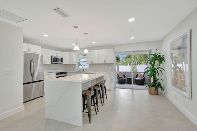 kitchen with a wealth of natural light, a center island, appliances with stainless steel finishes, and white cabinetry