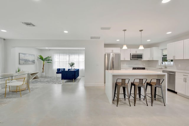 kitchen featuring sink, appliances with stainless steel finishes, a center island, and white cabinetry