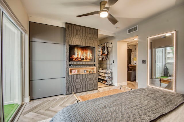 bedroom featuring a fireplace, ensuite bath, and light parquet floors