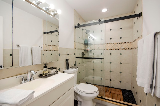 bathroom featuring vanity, tile walls, toilet, and a shower with door