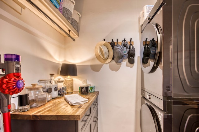 clothes washing area with cabinets and stacked washer / drying machine