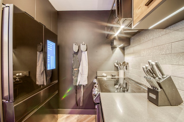 kitchen featuring light wood-type flooring, black refrigerator, and stainless steel stove