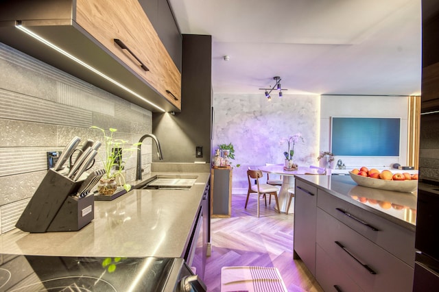 kitchen featuring stainless steel stove, stainless steel counters, sink, and light parquet flooring