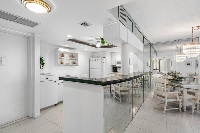 1147 Hillsboro Mile Unit 701, Hillsboro Beach, FL 33062 - kitchen with freestanding refrigerator, white cabinetry, ceiling fan with notable chandelier, and light tile patterned flooring