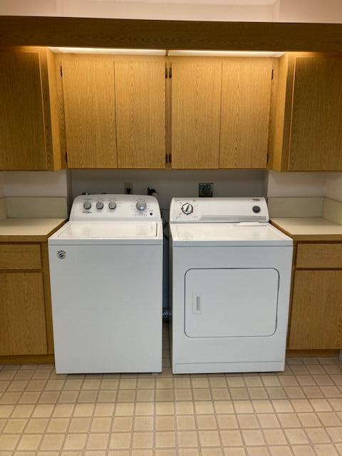 laundry room with separate washer and dryer, cabinets, and light tile patterned floors