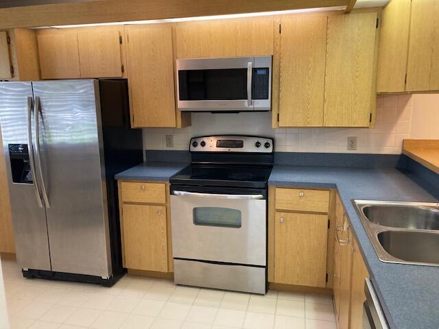 kitchen featuring stainless steel appliances, backsplash, and sink