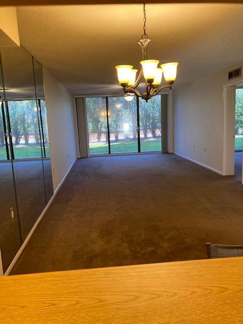 empty room featuring dark carpet and an inviting chandelier