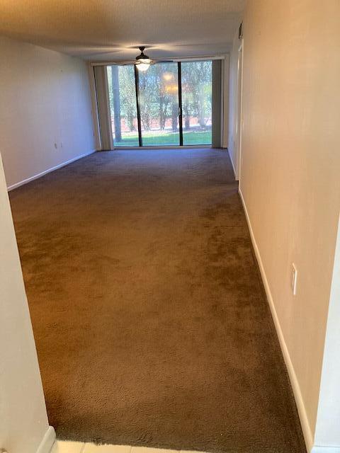 empty room featuring dark carpet and ceiling fan