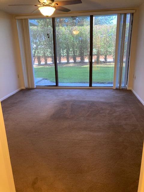 spare room featuring plenty of natural light, dark carpet, and ceiling fan