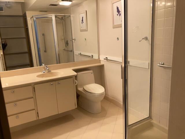 bathroom featuring vanity, a shower with shower door, and toilet