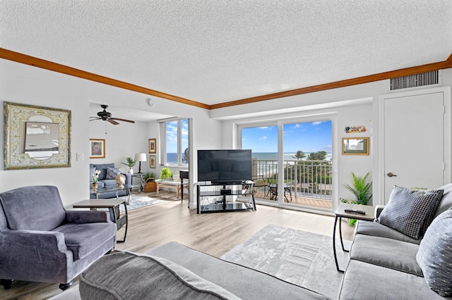 living room featuring light hardwood / wood-style flooring, ornamental molding, a textured ceiling, and ceiling fan