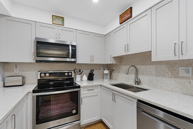 kitchen with appliances with stainless steel finishes, decorative backsplash, white cabinets, and sink