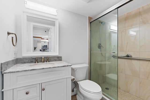 bathroom with a shower with door, vanity, and toilet