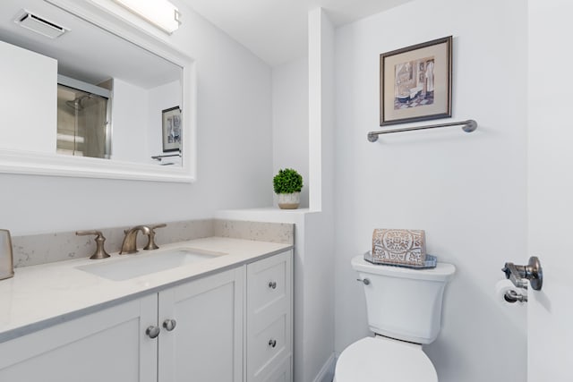 bathroom with vanity, a shower with shower door, and toilet