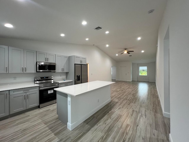 kitchen with gray cabinetry, light wood-type flooring, lofted ceiling, and stainless steel appliances