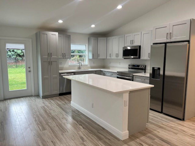 kitchen with light hardwood / wood-style floors, lofted ceiling, a center island, gray cabinetry, and appliances with stainless steel finishes