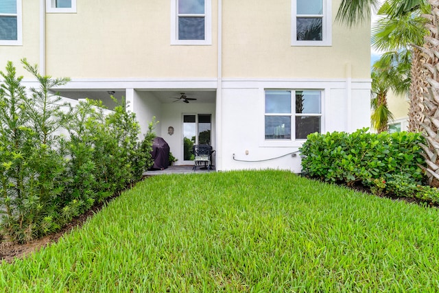 property entrance with a patio, a lawn, and ceiling fan