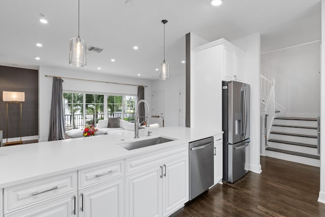 kitchen with appliances with stainless steel finishes, hanging light fixtures, sink, and white cabinetry