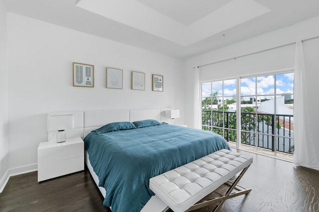 bedroom featuring access to outside, a tray ceiling, and dark hardwood / wood-style floors