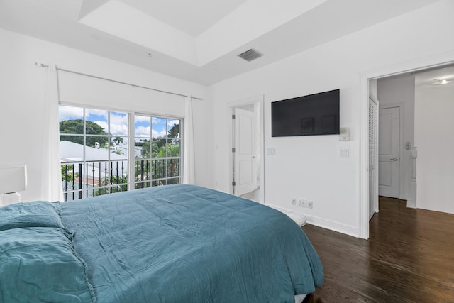 bedroom featuring access to outside, a tray ceiling, and dark hardwood / wood-style flooring