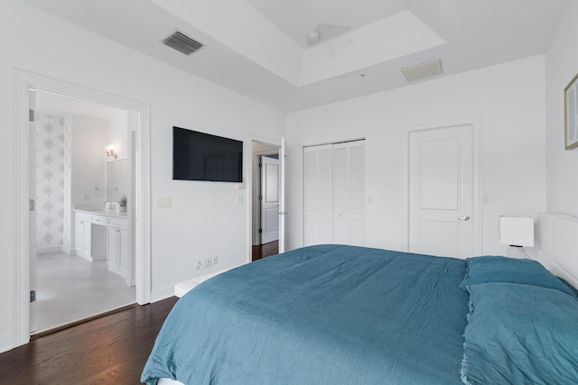 bedroom with dark wood-type flooring and connected bathroom