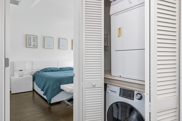 laundry room with stacked washer / drying machine and dark hardwood / wood-style flooring