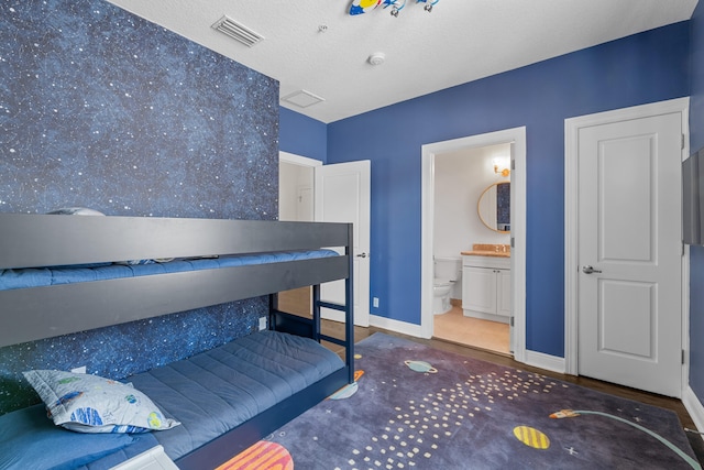 bedroom featuring a textured ceiling and ensuite bath