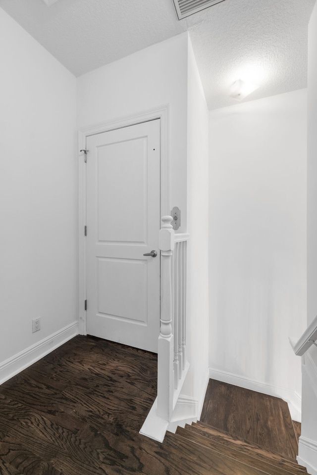 corridor with dark hardwood / wood-style floors and a textured ceiling