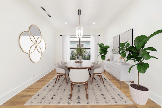 dining area with light hardwood / wood-style floors and a chandelier