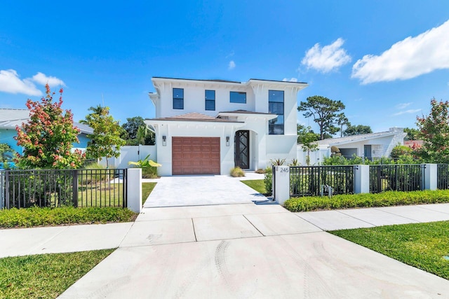 245 Alhambra Pl, West Palm Beach, FL 33405 - modern home featuring concrete driveway, stucco siding, fence private yard, and a garage