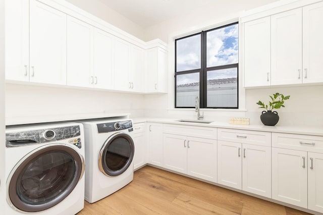 washroom featuring separate washer and dryer, sink, light hardwood / wood-style floors, and cabinets