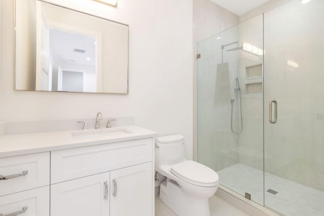 bathroom with vanity, toilet, and a shower with shower door