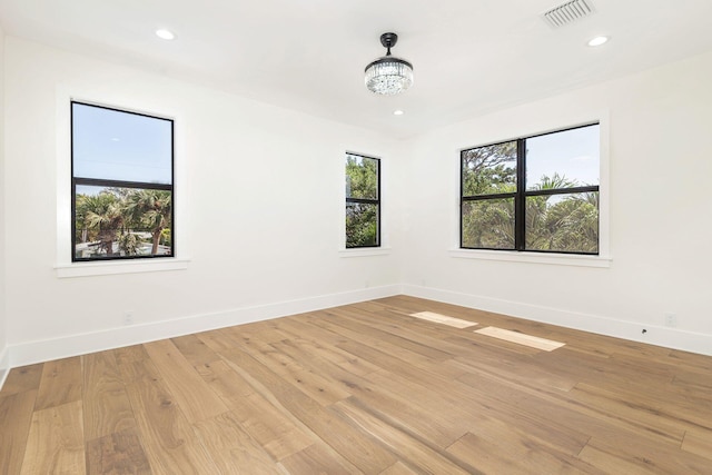 spare room with a chandelier and light hardwood / wood-style floors