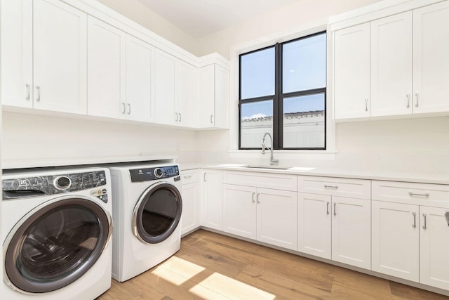 clothes washing area featuring cabinets, sink, independent washer and dryer, and light hardwood / wood-style flooring