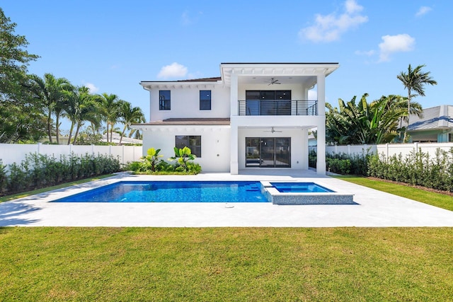 back of house with ceiling fan, a pool with hot tub, a balcony, and a lawn