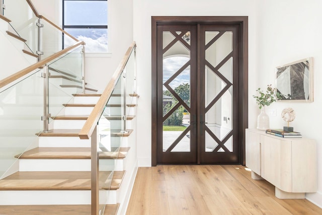 foyer with a healthy amount of sunlight, light hardwood / wood-style floors, and french doors