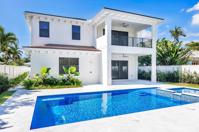 back of property featuring ceiling fan, a pool with hot tub, a balcony, and a patio area