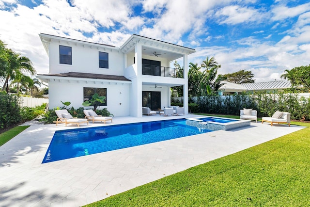 rear view of house with a balcony, ceiling fan, a pool with hot tub, an outdoor living space, and a patio area