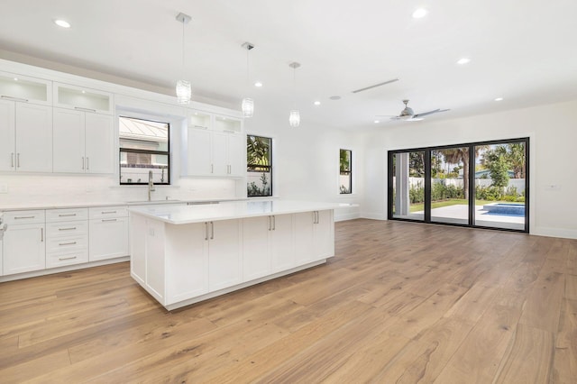 kitchen with light hardwood / wood-style floors, a kitchen island, and white cabinetry