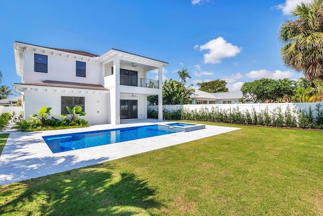 back of property with a balcony, a lawn, ceiling fan, a pool with hot tub, and a patio area