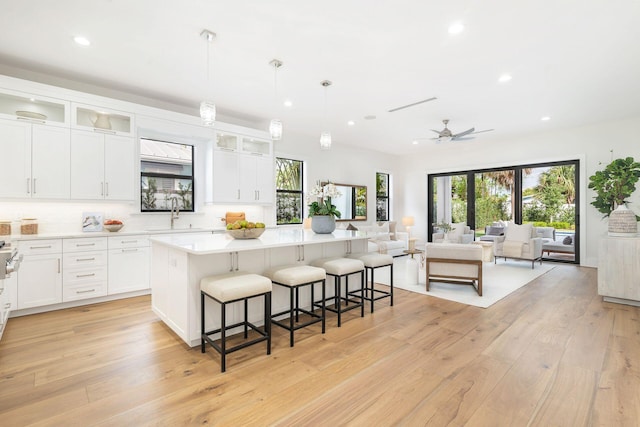 kitchen with hanging light fixtures, white cabinetry, a kitchen island, and a breakfast bar