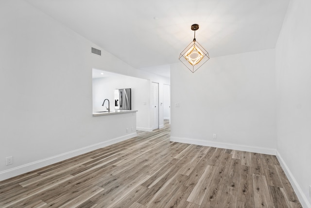 unfurnished dining area featuring hardwood / wood-style flooring, a notable chandelier, and lofted ceiling