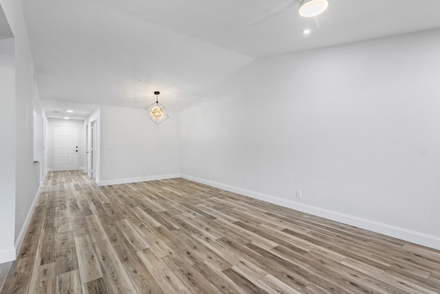 empty room with vaulted ceiling and light hardwood / wood-style floors